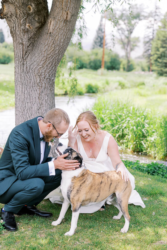 Bride and Groom kneel with their dog as part of their First Look on their wedding day