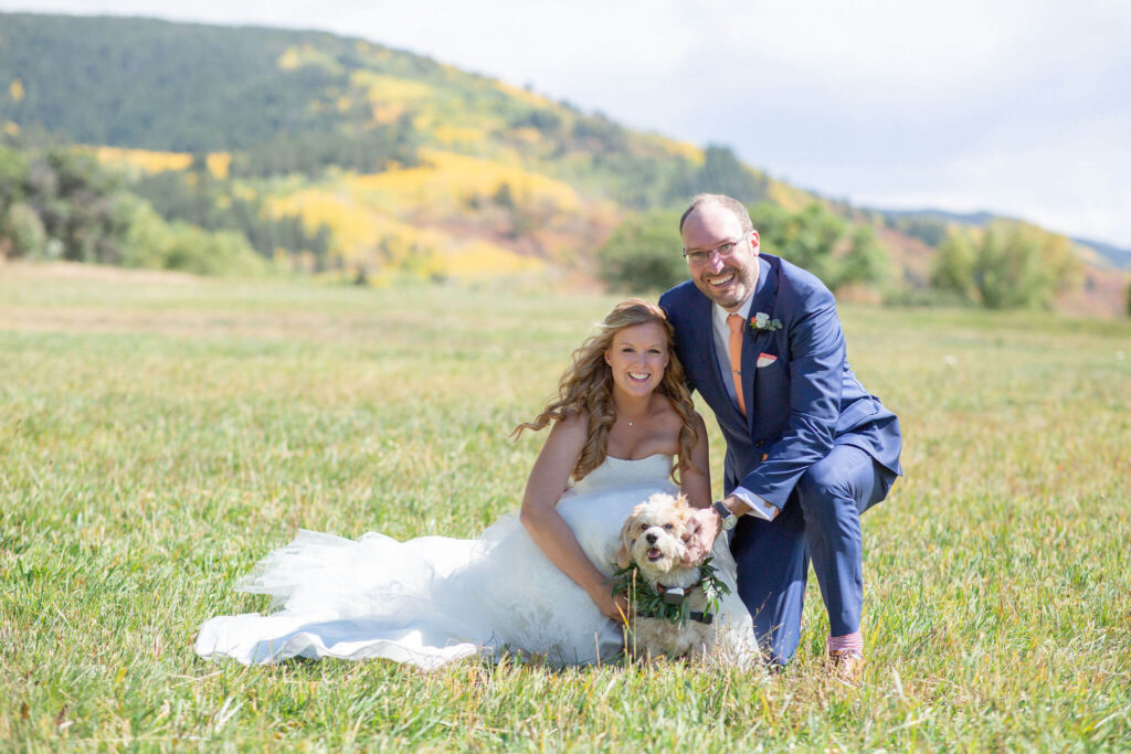 Bride and groom pose with their dog in an Aspen meadow before their wedding