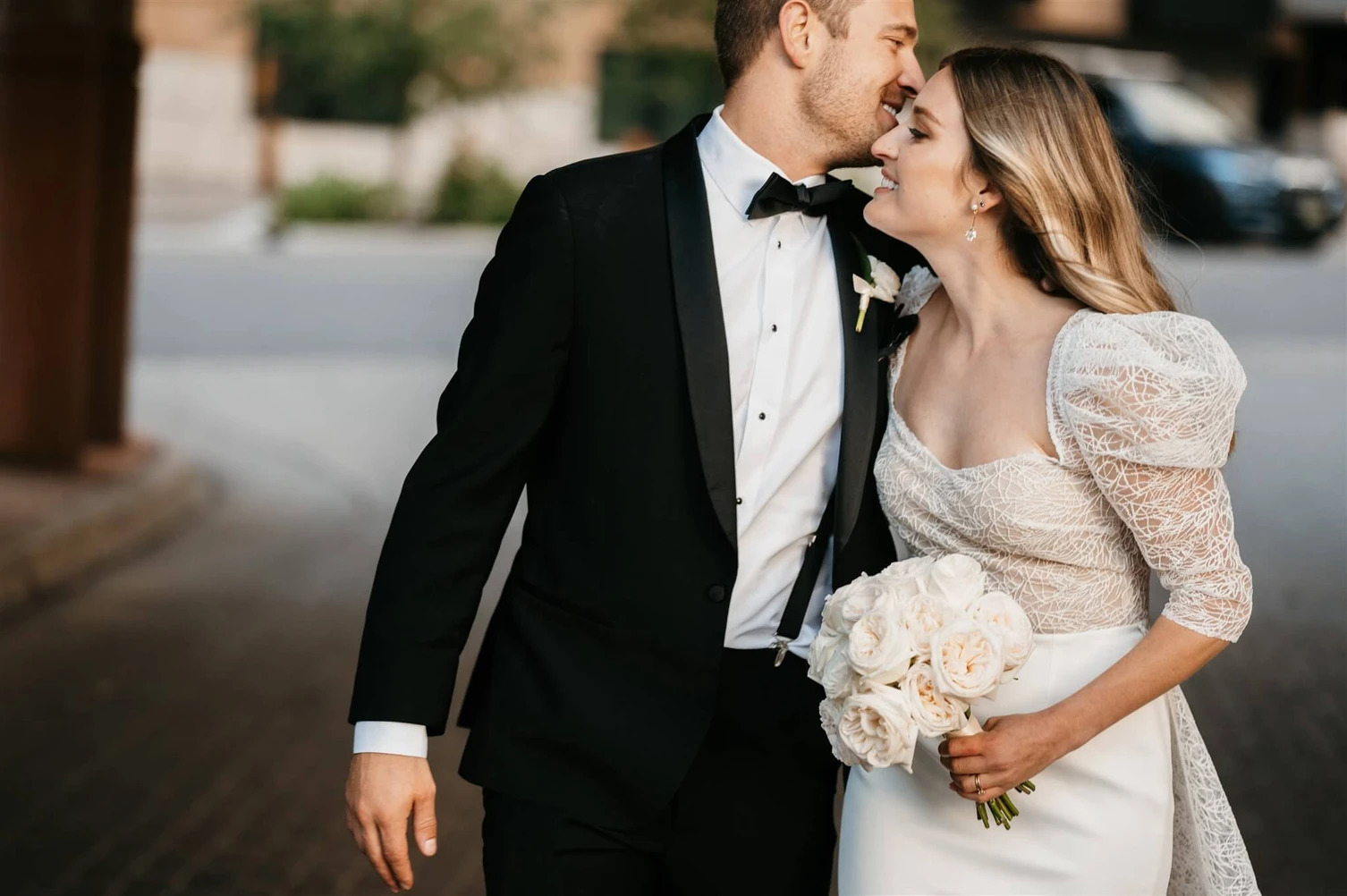 A happy couple sharing a joyful moment after their wedding ceremony, surrounded by beautiful mountain scenery. The bride is wearing a stunning lace wedding gown and holding a bouquet of white roses, while the groom is dressed in a classic tuxedo. This image captures the essence of a romantic celebration at a Colorado wedding venue, perfect for couples seeking local wedding vendors and picturesque Aspen or mountain wedding venues.