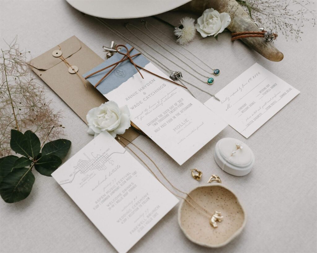 A wedding invitation suite is artfully laid out with a few flowers and bridal accessories.