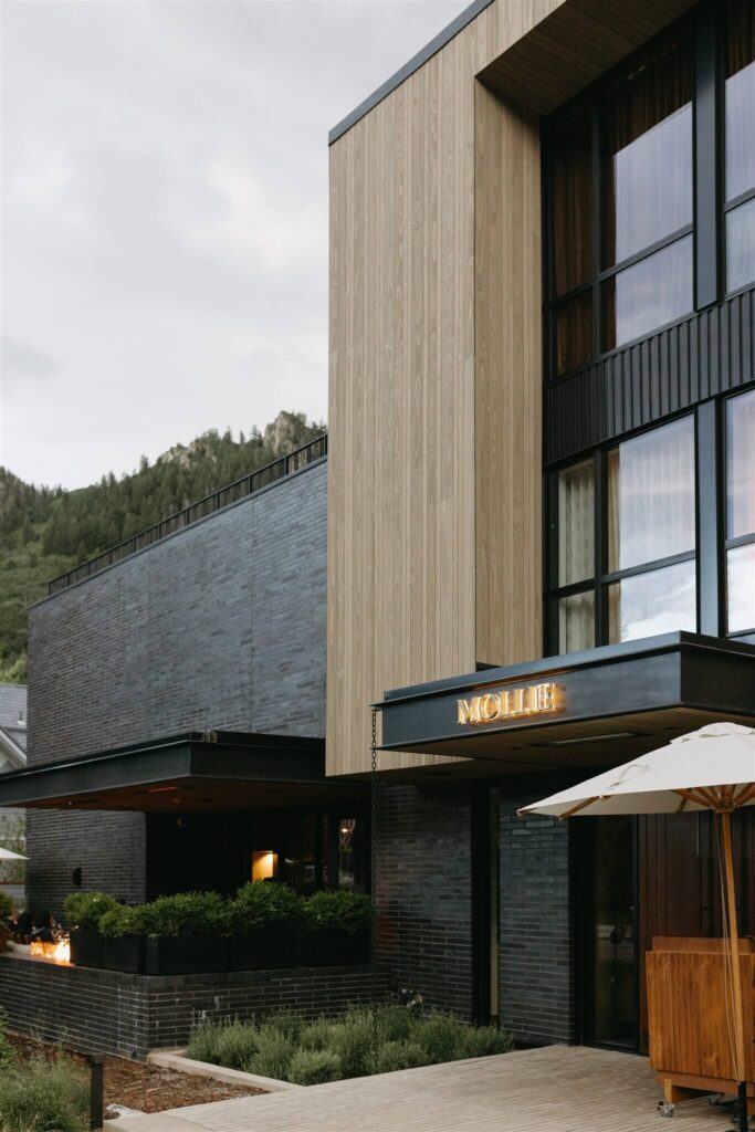 Exterior view of the MOLLIE Aspen wedding venue featuring a sleek design with textured wood and stone.