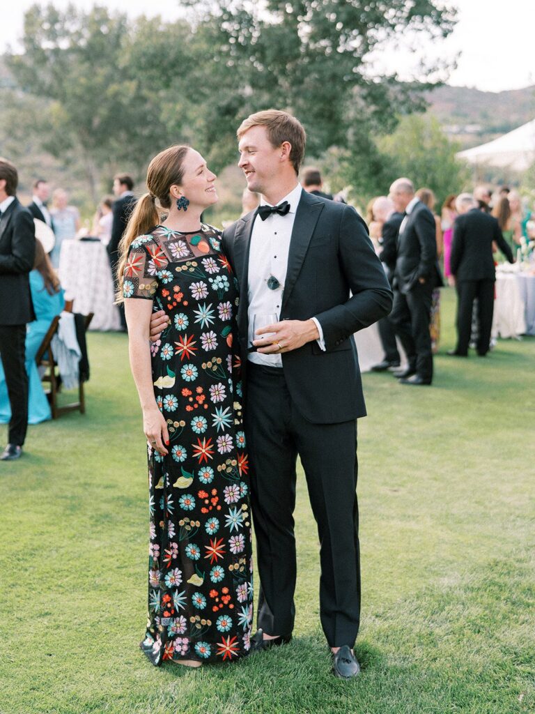 couple in black tie wedding guest attire at an aspen mountain wedding, black tuxedo with a bow tie and a floral embroidered evening gown