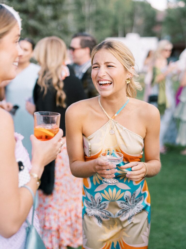 young wedding guest in a printed halter dress at an aspen summer wedding, bold retro floral pattern at cocktail hour